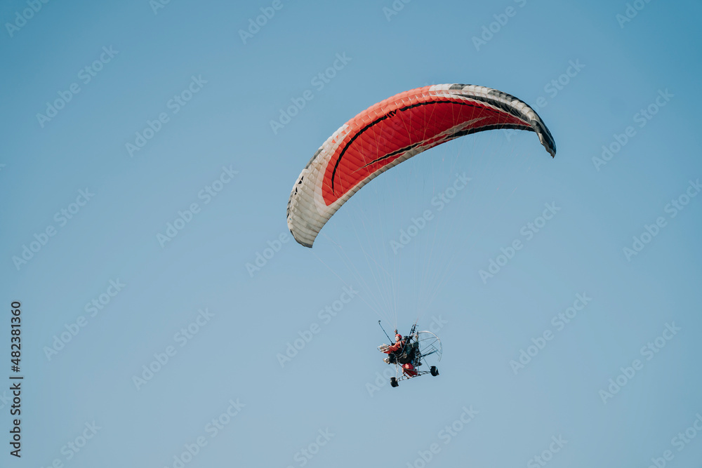 A female tourist is flying with a paramotor pilot in the sky to look at the scenery. Thailand's tourism industry A female tourist is flying with a paramotor pilot in the sky to look at the scenery. Thailand's tourism industry
