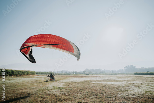 A female tourist is flying with a paramotor pilot in the sky to look at the scenery. Thailand's tourism industry