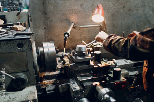 Turner worker working on old lathe machine at factory