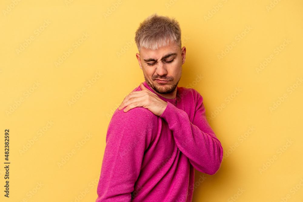 Young caucasian man isolated on yellow background having a shoulder pain. Young caucasian man isolated on yellow background having a shoulder pain.