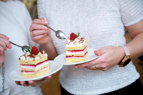 close-up of two women's hands eating cream cake decorated with berries © Zelma