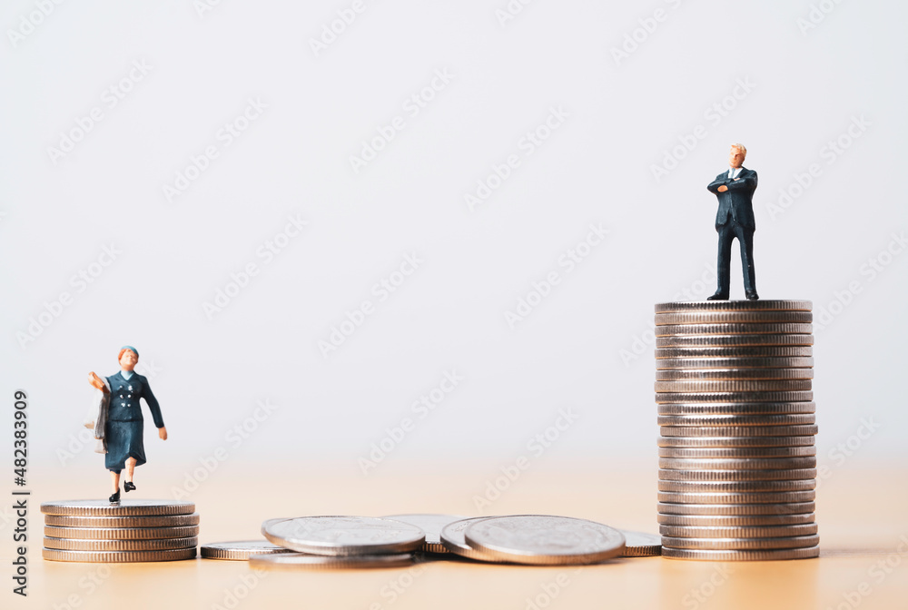 Miniature figure of businessman standing on highest coins and businesswoman standing on lowest coins stacking for inequality gender in company concept. Miniature figure of businessman standing on highest coins and businesswoman standing on lowest coins stacking for inequality gender in company concept.