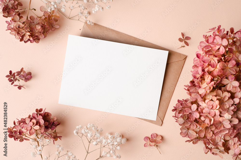 Invitation card mockup with envelope, dry hydrangea and gypsophila flowers decorations. Blank greeting card mockup.
