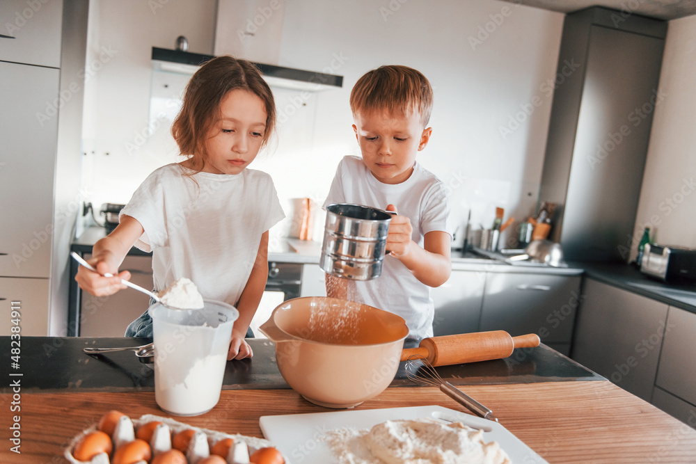 New year anticipation. Little boy and girl preparing Christmas cookies on the kitchen