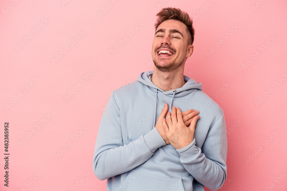 Young caucasian man isolated on pink background laughing keeping hands on heart, concept of happiness. Young caucasian man isolated on pink background laughing keeping hands on heart, concept of happiness.