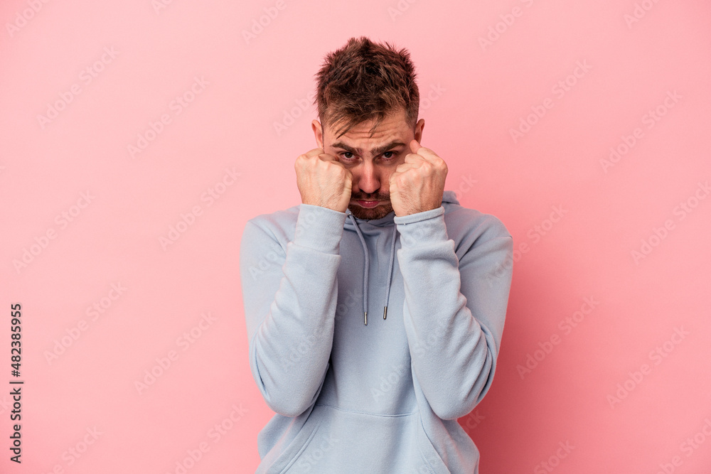 Young caucasian man isolated on pink background throwing a punch, anger, fighting due to an argument, boxing. Young caucasian man isolated on pink background throwing a punch, anger, fighting due to an argument, boxing.