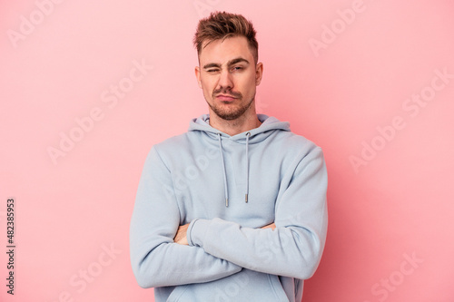 Young caucasian man isolated on pink background unhappy looking in camera with sarcastic expression. © Asier