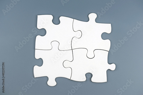 Four white puzzle pieces on gray background. Concept of teamwork, solving problems