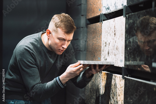 a man chooses a natural stone product in a specialized store, comparison of material samples from different manufacturers