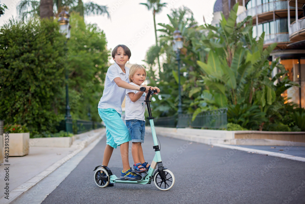 Cute preteen boy, riding scooter in Monaco village on sunset Cute preteen boy, riding scooter in Monaco village on sunset