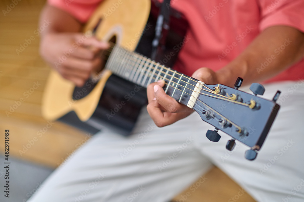 Hands of dark-skinned man playing guitar