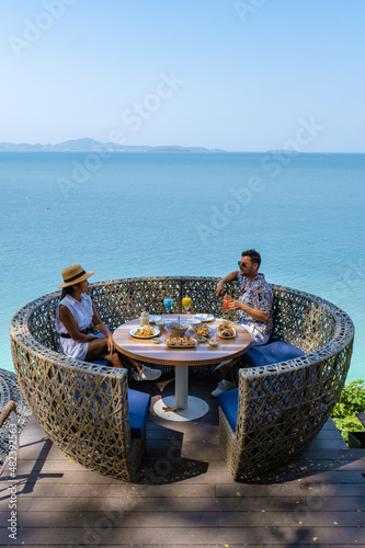 couple having lunch at a restaurant looking out over the ocean of Pattaya Thailand, man and woman having dinner in a restaurant by the ocean in Pattaya. 