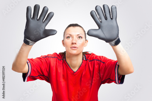 Soccer Concepts. Sportive Caucasian Football Female Player Athlete Posing As Goalkeeper With Black Gloves and Red Sport Outfit Against White