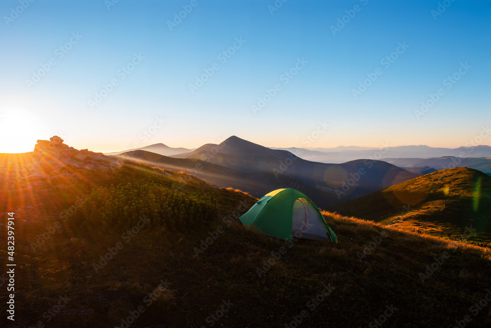 Green camping tent on top of mountain with amazing view