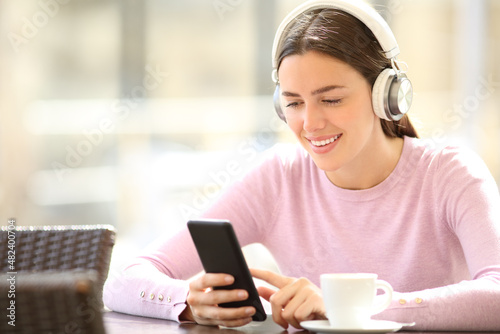 Happy woman checking phone listening to music in a bar