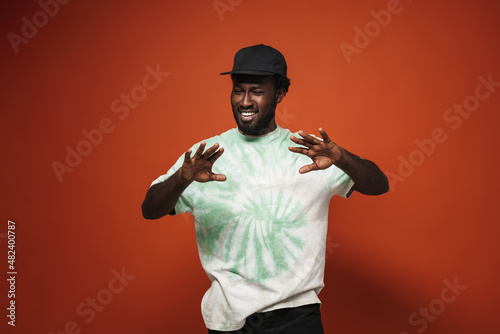Young black man wearing cap gesturing and smiling at camera