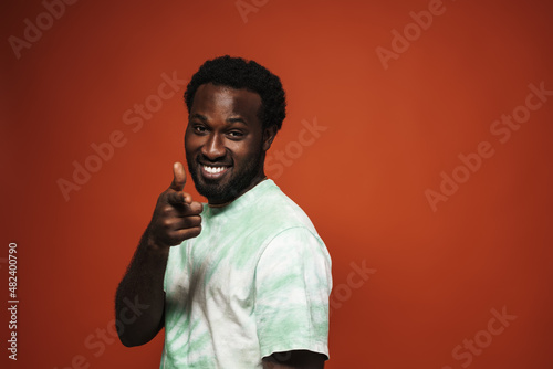 Young black man with beard smiling and pointing finger at camera