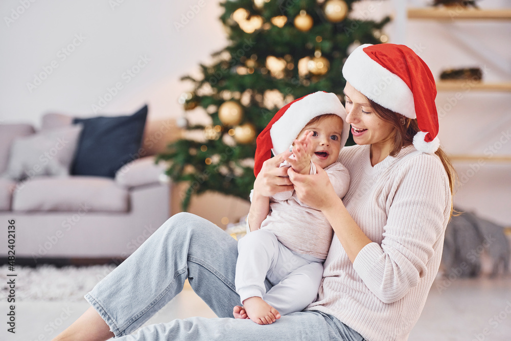 Playing with each other. Mother with her little daughter is indoors at home together Playing with each other. Mother with her little daughter is indoors at home together