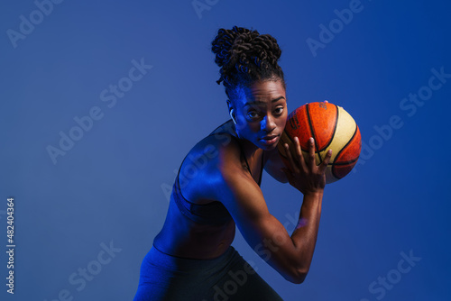 Black young sportswoman in earphones working out with basketball © Drobot Dean