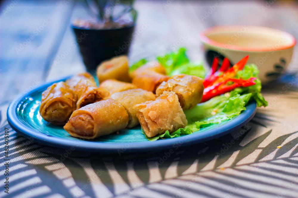 Deep fried spring rolls in blue plates with vegetables, chili and dipping sauce (Chinese food) Deep fried spring rolls in blue plates with vegetables, chili and dipping sauce (Chinese food)