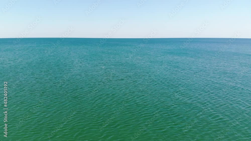 Aerial flight over the surface of the ocean. Smooth horizon in the clear sea. Marine background Aerial flight over the surface of the ocean. Smooth horizon in the clear sea. Marine background