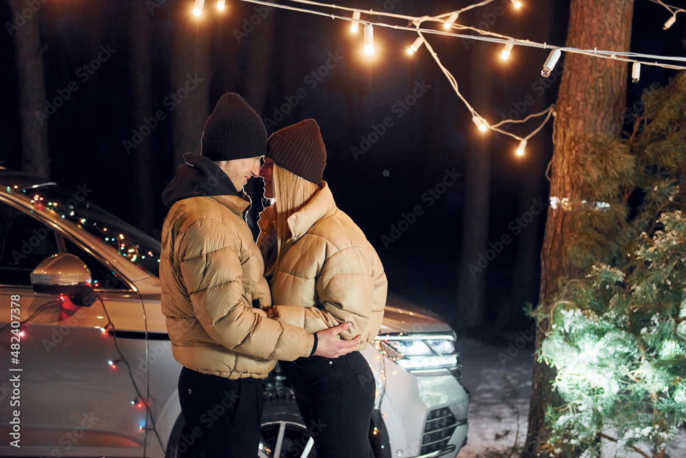 Fototapeta premium Looking at each other. Couple standing in the forest and celebrating New year