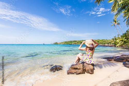 Young Asian lady tourist sitting on the rock in to the beach on her holiday.