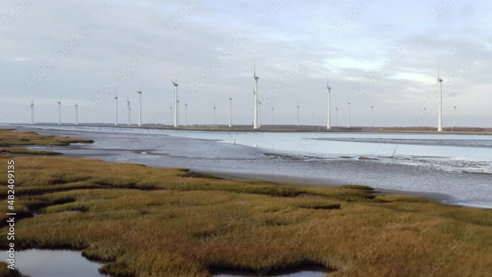 Windfarm near tidal area and dyke protecting adjacent polder from sea Windfarm near tidal area and dyke protecting adjacent polder from sea