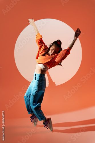 Happy woman dancing with raised hands in studio photo