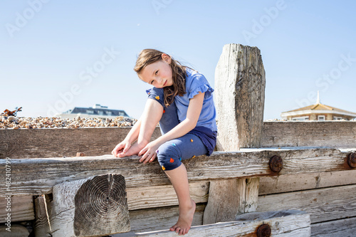 Portrait of girl (4-5) sitting on wooden structure on beach photo