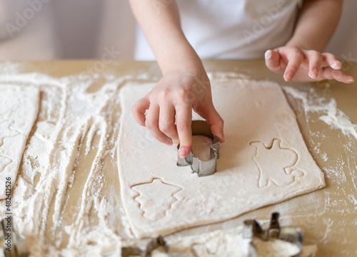 Children's hands press the mold on the dough, making cookies