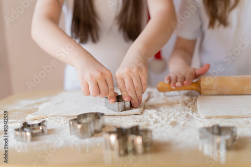 Children's hands press the mold on the dough, making cookies