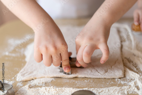 Children's hands press the mold on the dough, making cookies