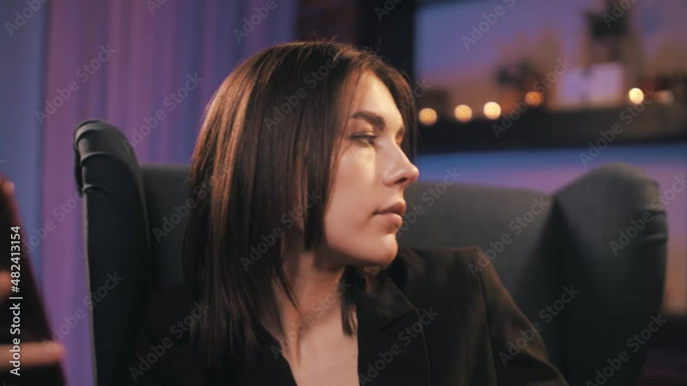 beautiful girl sitting in an armchair looking at the phone and drinking wine in her house beautiful girl sitting in an armchair looking at the phone and drinking wine in her house