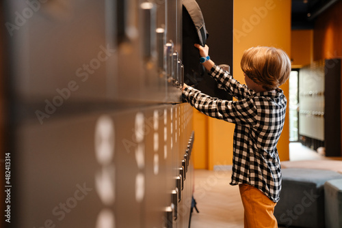 White boy putting his backpack in checkroom at school photo