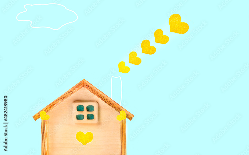 Wooden model of a house with a chimney and hearts in the form of smoke. A joyful happy picture of family comfort. The concept of love, family and celebration