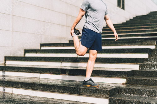 Young athlete man runner running up and down on city stairs in summer on morning run, background urban city street. Sports training. Fitness cardio workout in fresh air, walk outside.