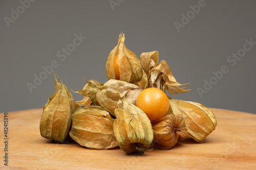 Pile of ripe physalis fruits on a wooden table. Close up studio shot, front view