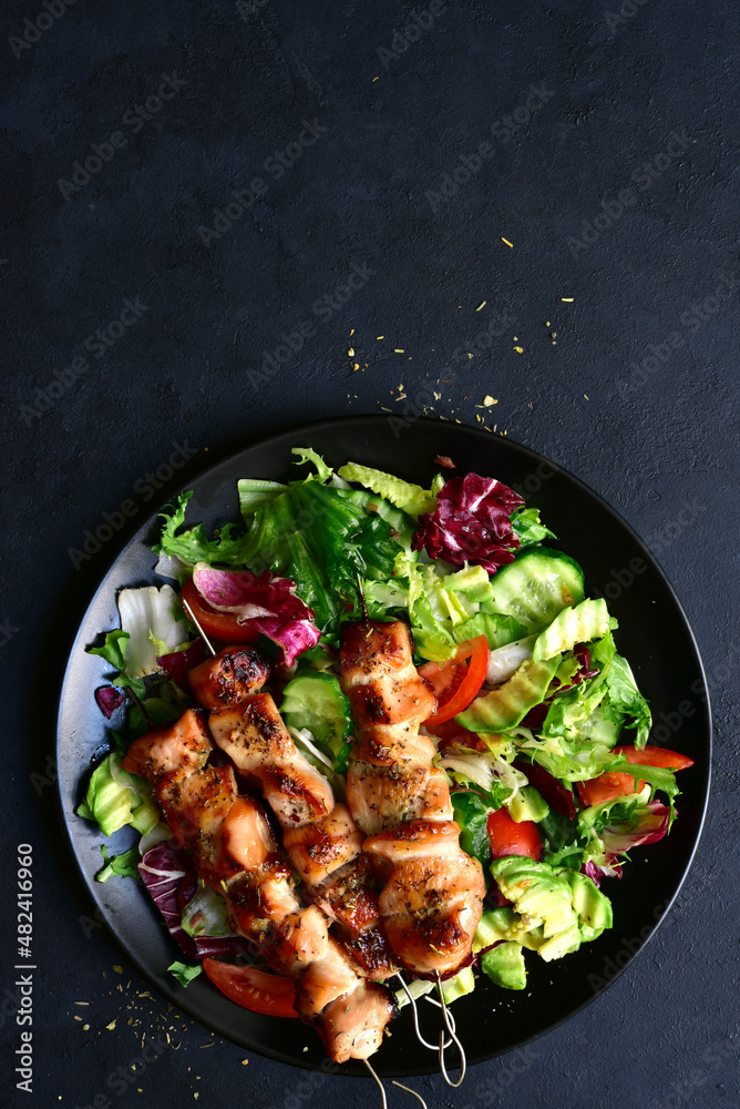 Chicken kebab skewers with fresh vegetable salad. Top view with copy space. Chicken kebab skewers with fresh vegetable salad. Top view with copy space.