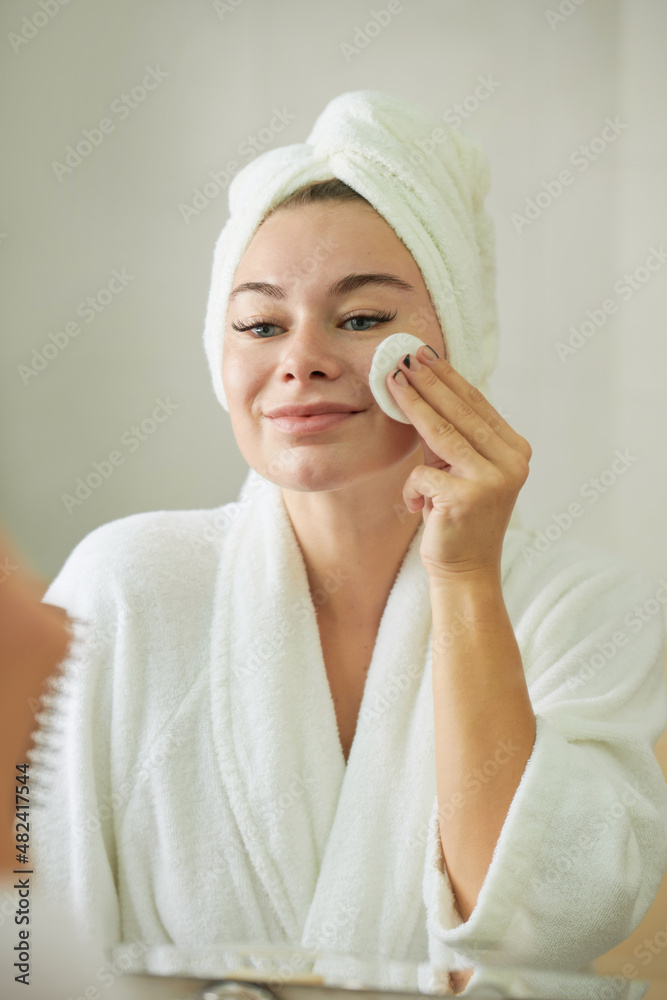 Smiling young woman enjoying beauty morning routine after shower