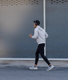 Young man wearing sportwear jogging on road,