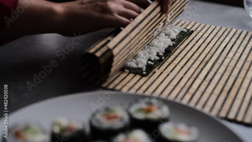 a woman prepares sushi rolls at home according to a master class. a girl cooks a Japanese dish sushi rolls in the kitchen on a video recipe