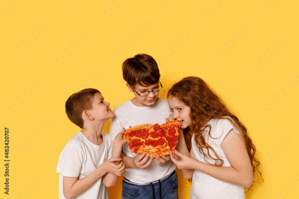 Children eating pizza on yellow background. Children eating pizza on yellow background.