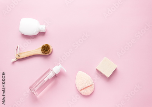 Flat lay composition with cosmetic products and accessories on a pink pastel background. Top view