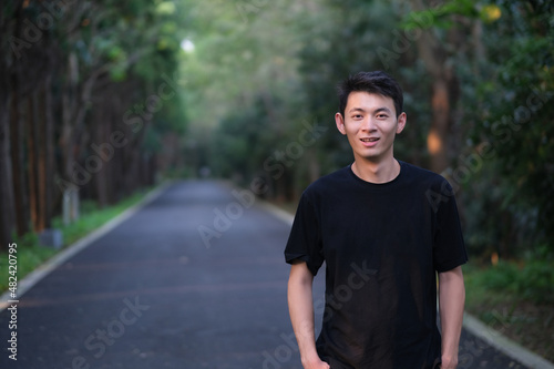 handsome Asian young man smiling and looking at camera in natural forest park
