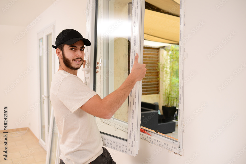 handsome young professional man installing and replacing a new home window in client house for improvement energy saving efficiency isolation handsome young professional man installing and replacing a new home window in client house for improvement energy saving efficiency isolation