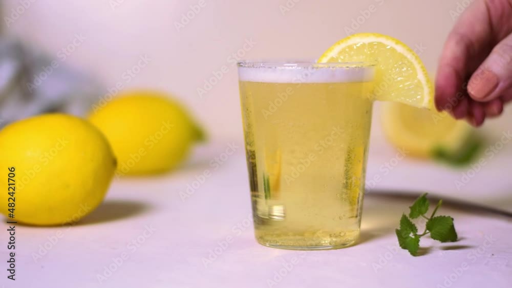 Pouring sparkling lemonade into the glass, decorating it with mint and putting a metal straw. Refreshing lemon soft drink Pouring sparkling lemonade into the glass, decorating it with mint and putting a metal straw. Refreshing lemon soft drink