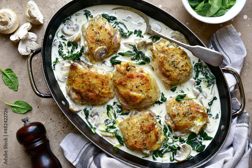 Chicken thighs stewed in cream sauce with mushrooms and spinach. Top view with copy space. Chicken thighs stewed in cream sauce with mushrooms and spinach. Top view with copy space.