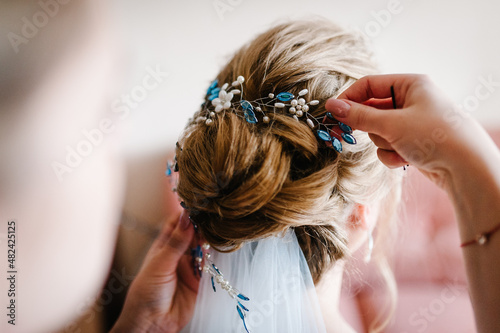 Mother hands holding ornaments and helping dressing veil bride. Bridesmaid preparing bride, helping fasten veil. Getting ready. Wedding concept preparations.