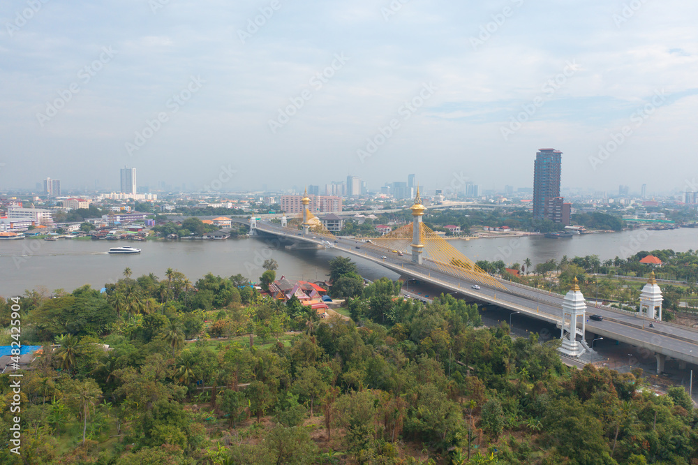 Aerial view of Maha Chesadabodindranusorn Bridge or Nonthaburi Bridge crossing Chao Phraya River and Bangkok skyline, Thailand. buildings in urban city.